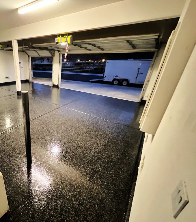 Dark flake epoxy garage floor at night, door open